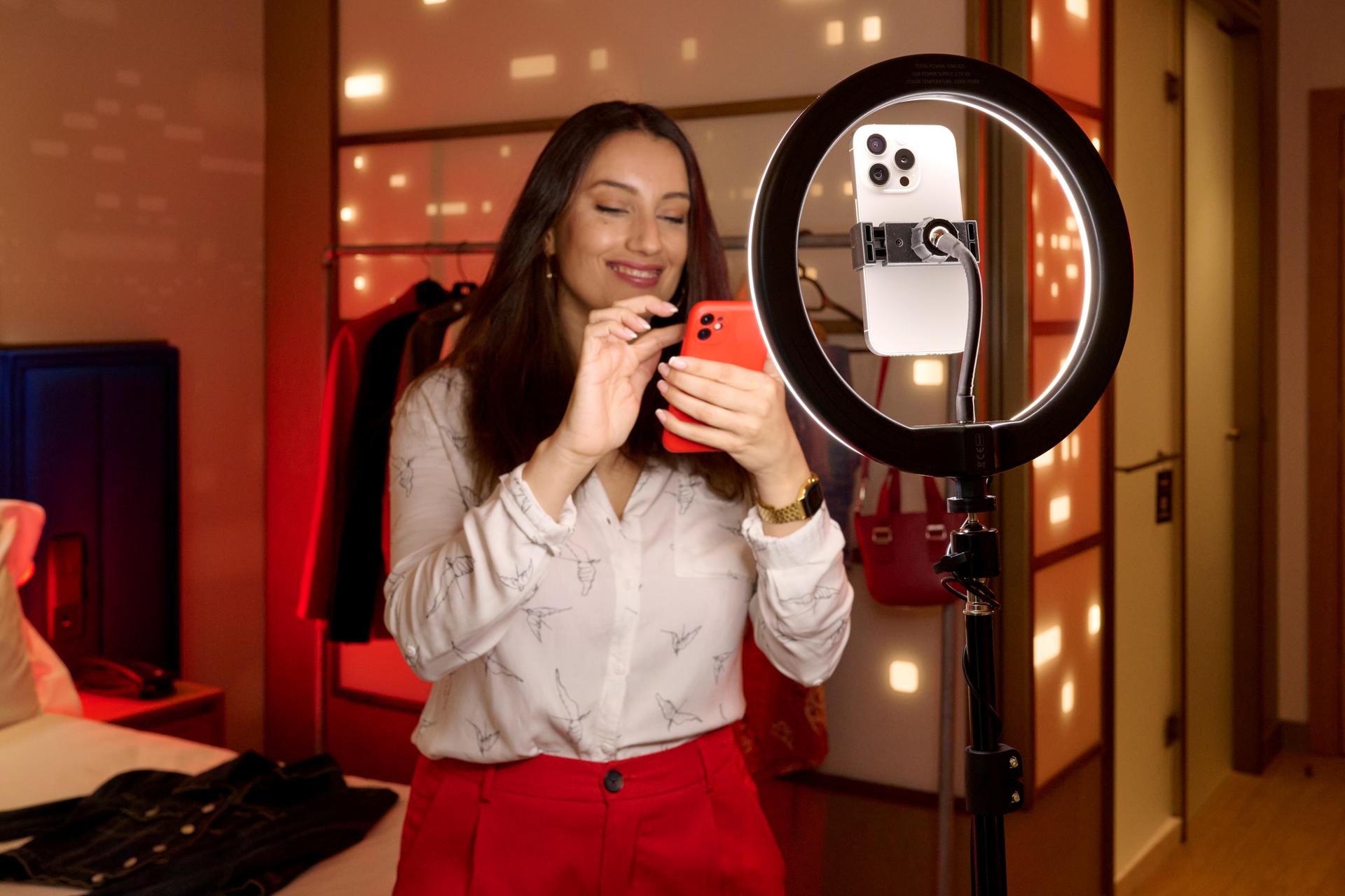 Mujer sonriente sosteniendo teléfono móvil mientras interactúa en redes sociales